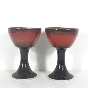 May include: Two red and black ceramic goblets with a flared base.