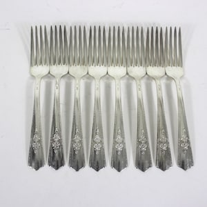May include: Ten silver forks with ornate designs on the handles.