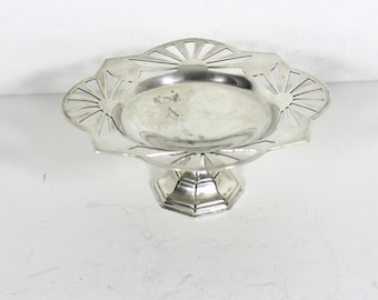 May include: A silver pedestal dish with a scalloped edge and a decorative sunburst design. The dish is on a white background.
