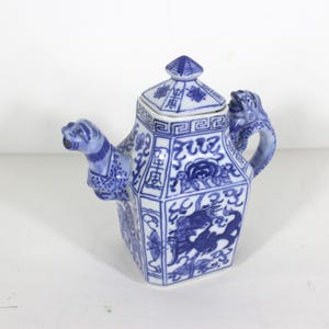 May include: A blue and white porcelain teapot with dragon and floral designs. The teapot has a square body with a lid and a spout shaped like a dragon's head. The handle is also shaped like a dragon's head.