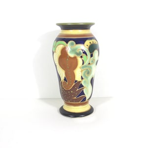 May include: A ceramic vase with a blue, brown, green, and yellow floral design. The vase has a rounded body and a flared lip.