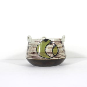 May include: A white ceramic planter with brown and green geometric designs and two white handles.