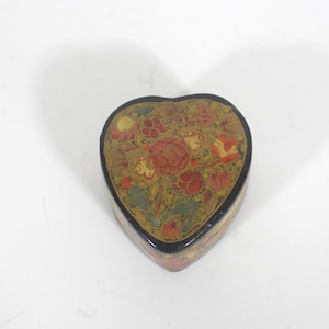 May include: A heart-shaped box with a black background and intricate floral designs in red, yellow, and green.