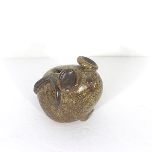 Peut inclure: Une figurine de souris en céramique avec un glaçage moucheté brun et vert. La souris est assise, les oreilles dressées et la queue enroulée autour de son corps.