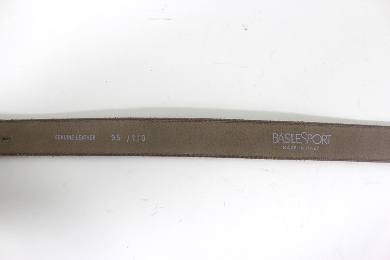 May include: A brown leather belt with the text "BASILESPORT MADE IN ITALY" and "GENUINE LEATHER 95 / 110" printed on it.