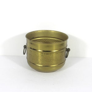 May include: A gold hammered metal planter with two handles. The planter is round and has a textured surface.