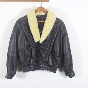 May include: A black leather jacket with a white faux fur collar. The jacket has a zip fastening and two pockets.