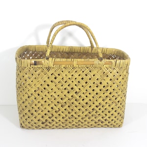 May include: A woven straw basket with two handles. The basket is rectangular and has a light brown color.