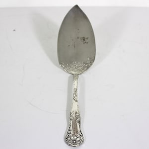 May include: A silver cake server with an ornate floral design on the handle.