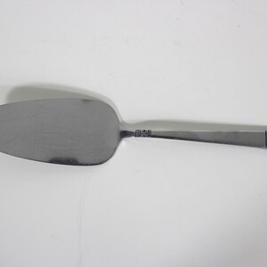 May include: A silver cake server with a decorative design on the handle.
