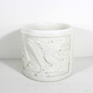 May include: White ceramic cylindrical vase with a carved dragon design.
