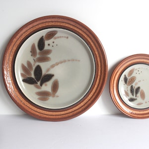Peut inclure: Ensemble d'assiettes en céramique brun et blanc avec un motif de feuilles. Les assiettes ont un bord brun avec plusieurs rayures.