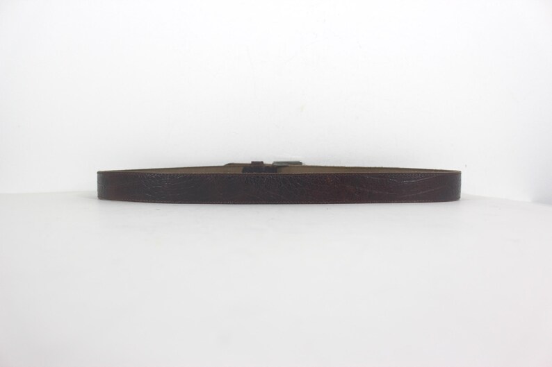May include: A brown leather belt with a silver buckle.