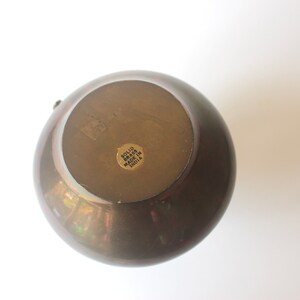 Pode incluir: Um vaso redondo de lat&atilde;o maci&ccedil;o com acabamento dourado. A parte inferior do vaso tem um adesivo que diz "Solid Brass Made in India".