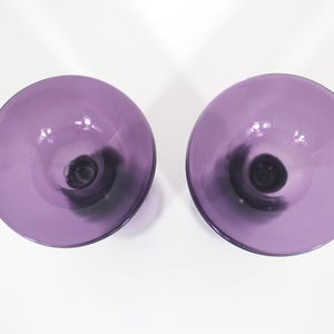 May include: Two purple glass candle holders with a black swirl design.