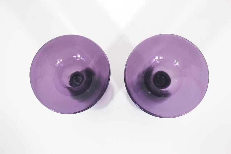 May include: Two purple glass candle holders with a black swirl design.
