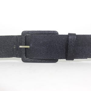 May include: A black leather belt with a large, square buckle. The belt is textured and has a subtle sheen.