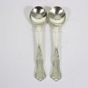 May include: Two silver spoons with ornate handles. The spoons have a polished finish and are in excellent condition.