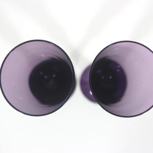 May include: Two purple glass wine glasses viewed from above. The glasses are empty and have a clear, smooth surface.