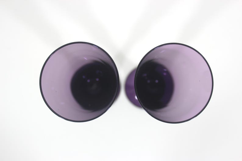 May include: Two purple glass wine glasses viewed from above. The glasses are empty and have a clear, smooth surface.