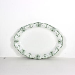 May include: Oval white serving platter with a scalloped edge and a green floral design. The platter is made of ceramic and is approximately 36 cm long.