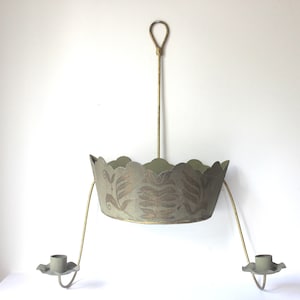 May include: A green metal candle chandelier with a decorative floral pattern. The chandelier has two candle holders and a hanging chain.