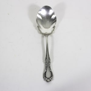 May include: A silver sugar spoon with an ornate handle and a scalloped bowl.