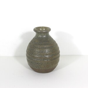 May include: A small, round, green ceramic vase with a textured surface.