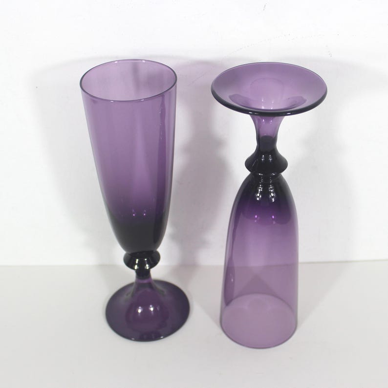 May include: Two purple glass goblets, one tall and slender, the other shorter and wider, with a flared top.