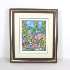 May include: Framed painting depicting a vibrant outdoor market scene. The artwork features figures in colorful clothing, surrounded by lush greenery, buildings, and a blue sky. The frame is a combination of brown and gold.