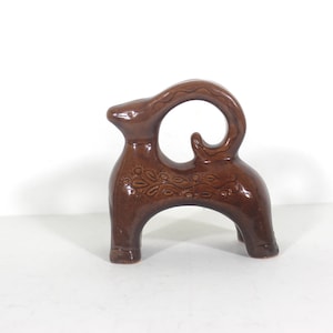 Peut inclure: Figurine en céramique marron représentant un animal stylisé avec une queue incurvée et des motifs floraux. La figurine a une finition brillante et repose sur trois pieds. La tête de l'animal est droite.