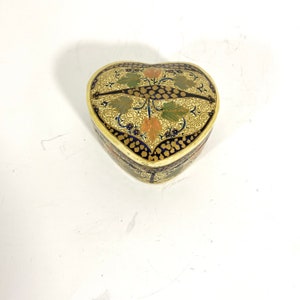 May include: A heart-shaped box with a decorative design. The box is made of paper and has a blue, gold, and green pattern.