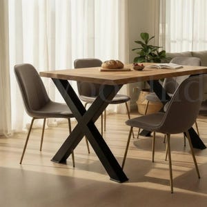 May include: A rectangular wooden dining table with black metal cross-shaped legs. Six grey upholstered chairs with gold-coloured legs are arranged around the table. The room is bright, with sheer curtains and a neutral colour scheme.