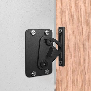 May include: Black metal door latch with a square plate and a lever handle. The latch is mounted to a wall and a door.