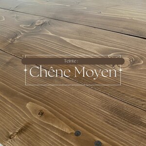 May include: Close-up of a wooden surface with a medium oak stain. The wood grain is visible, and the surface is made of planks. The text "Teinte: Ch&ecirc;ne Moyen" is displayed in a white font.