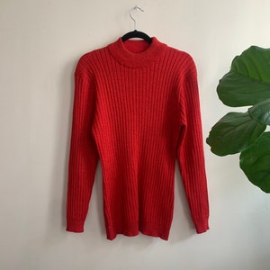 May include: A red ribbed turtleneck sweater with long sleeves.
