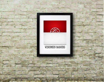 May include: Framed print with the Wisconsin Badgers logo. The artwork has a red and white colour scheme with a basketball graphic. The text "WISCONSIN BADGERS" is displayed at the bottom of the print. The frame is black.
