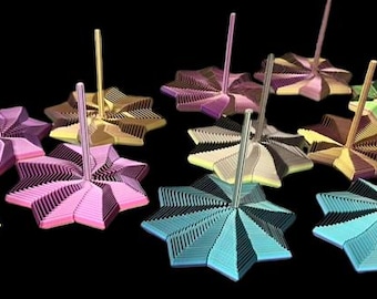 May include: A selection of star-shaped desk tidies in various colours. Each tidy has a central post and a multi-layered, fan-like design in shades of pink, blue, green, and gold. The desk tidies are set against a black background.