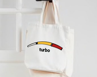 May include: Cream-coloured canvas tote bag with a black handle. The bag displays a curved graphic with yellow, red, and white segments, and the word "turbo" in black. The bag is hanging on a door.