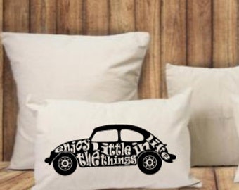May include: White cushions on a wooden surface. One cushion features a black silhouette of a vintage car with the text "enjoy little in the things". The cushions are square and rectangular.