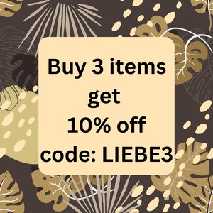 May include: A beige square with black text that reads "Buy 3 items get 10% off code: LIEBE3". The square is on a brown background with a pattern of beige leaves and dots.