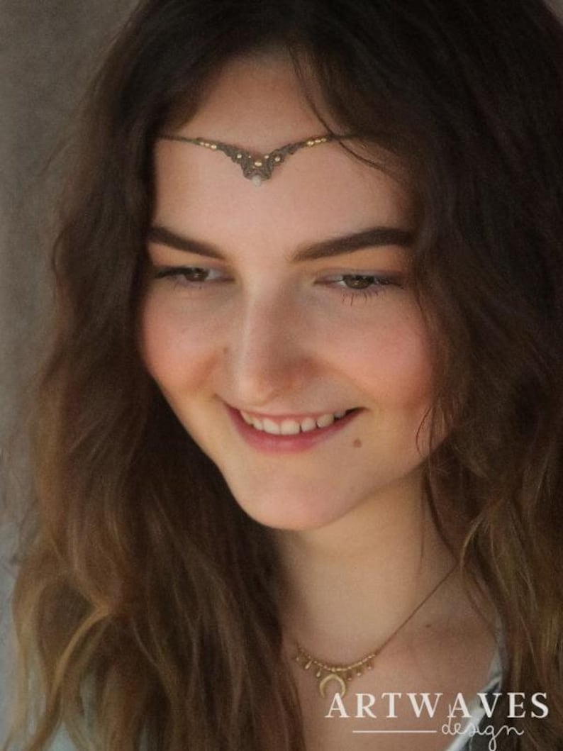 Puede incluir: Una mujer con cabello largo y casta&ntilde;o lleva una cadena de frente dorada con un colgante de perla. Tambi&eacute;n lleva un collar de oro con un colgante de media luna. El texto "ARTWAVES design" es visible en la esquina inferior derecha de la imagen.