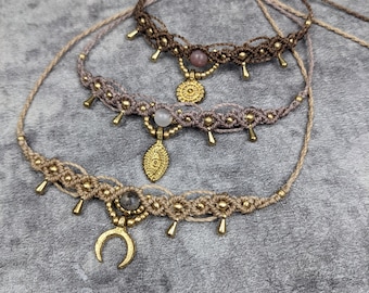 May include: Three layered macrame anklets with gold beads and charms. The top anklet has a round gold charm, the middle anklet has a leaf-shaped charm, and the bottom anklet has a crescent moon charm.