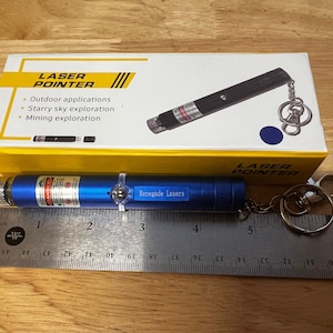 May include: A blue laser pointer with a keychain attached. The laser pointer is about 3 inches long and has a green laser beam. The laser pointer is labeled "Renegade Lasers".