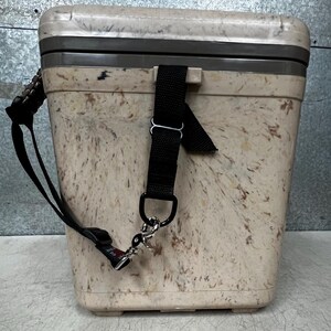 Pode incluir: Uma geleira bege salpicada com uma al&ccedil;a preta e acess&oacute;rios prateados. A geleira tem formato retangular com tampa e uma al&ccedil;a preta para transporte. O exterior apresenta um padr&atilde;o salpicado com tons de castanho e bege.