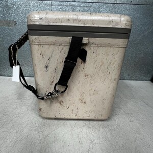 Pode incluir: Um cooler bege com um padr&atilde;o salpicado, uma al&ccedil;a de ombro preta e uma al&ccedil;a preta. O cooler tem formato retangular com uma moldura cinza ao redor da tampa. Uma etiqueta branca pende da al&ccedil;a.