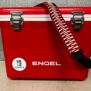 K&ouml;nnte beinhalten: Rote K&uuml;hlbox mit einem wei&szlig;en Streifen und einem schwarzen Gurt. Die K&uuml;hlbox hat einen wei&szlig;en Aufkleber mit der Aufschrift "19 Quarts" und das Wort "ENGEL" ist auf der Vorderseite aufgedruckt.