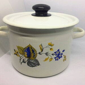May include: White enamel pot with a black lid and floral design featuring blue and yellow flowers.