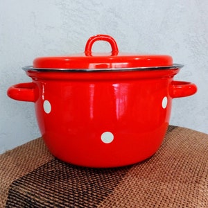May include: Red enamel pot with white polka dots and a lid. The pot has two handles on the sides.