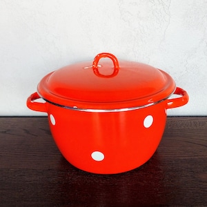 May include: A red enamel pot with white polka dots and a lid. The pot has two handles and a silver rim.